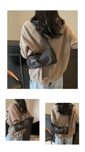 Detail of black cylinder crossbody bag with adjustable wide strap shown on model