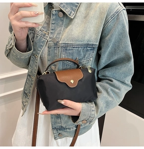 Close-up of black nylon dumpling tote with brown leather handles and gold hardware detailing