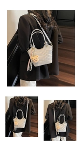 Detail showing wavy texture of silver-grey bucket bag with a brown teddy bear pendant
