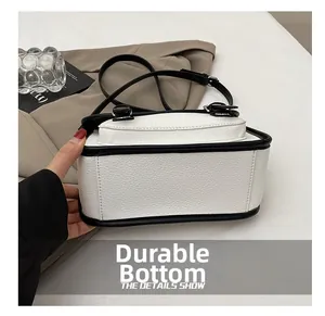 Detail view of durable white lychee texture base with contrast black edges on messenger bag