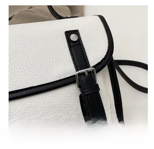Close-up of black and white lychee leather texture with silver metal pin buckle detail