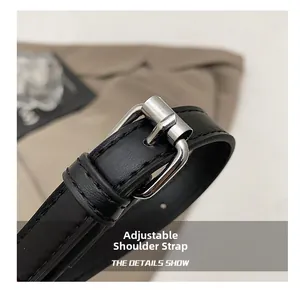 Detail of black leather adjustable shoulder strap with silver buckle on messenger bag