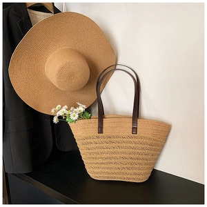 Close-up of woven straw tote bag featuring brown leather handles and interior lining