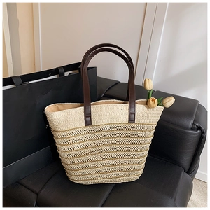 Detail of hand-woven straw tote bag with brown leather handles and interior lining