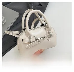 Detailed shot of cream faux leather handbag featuring silver chain and metal ring accents