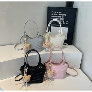 Detailed view of wave textured bucket bags in silver, white, black, and pink colors