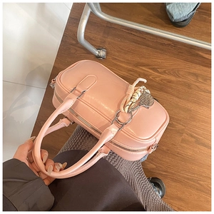 Détail du sac bowling rose en cuir avec breloque tressée et fermeture éclair