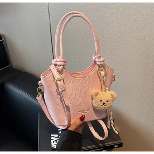 Gros plan du sac seau rose texturé avec breloque ours et détails du logo