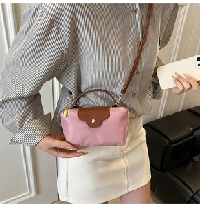 Close-up of pink nylon mini crossbody bag with brown leather flap and golden button