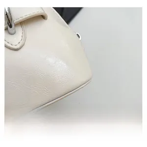 Close-up of minimalist cream white shell bag showing fine leather texture and neat stitching