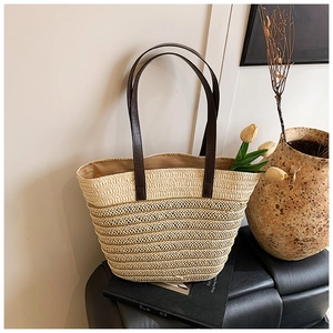 Detail of hand-woven straw tote bag with brown leather straps and striped texture