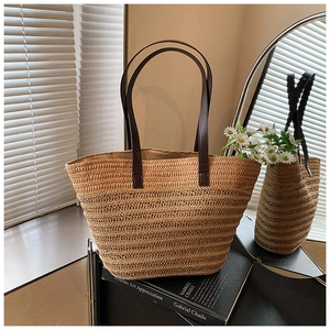 Detail of hand-woven straw tote bag with dual-texture mesh pattern and leather straps