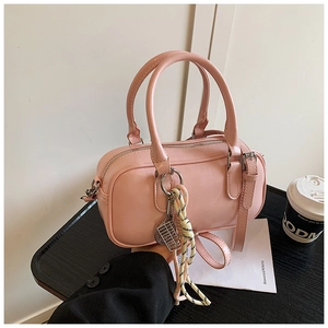 Détail du sac bowling rose avec poignée en corde rayée et petit pendentif boulier
