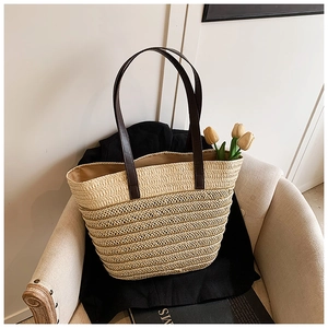 Detailed texture of beige woven straw tote bag with brown handles on a white sofa