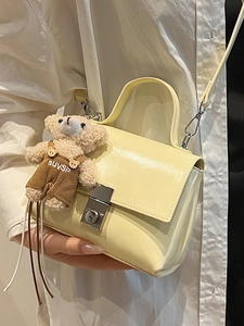 Minimalist pale yellow patent leather handbag with silver clasp and cute teddy bear charm