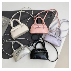 Detailed view of minimalist shell bags in beige, pink, purple, silver and black leather