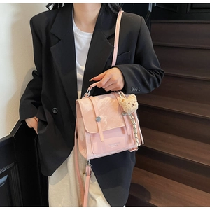 Pink glossy leather handbag with marble texture and cute teddy bear charm on side