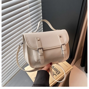 Detail of off-white lychee grain leather messenger bag with flap and dual buckle straps