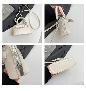 Detail view of cream mini shell bag showing silver hardware, zipper, and smooth PU leather