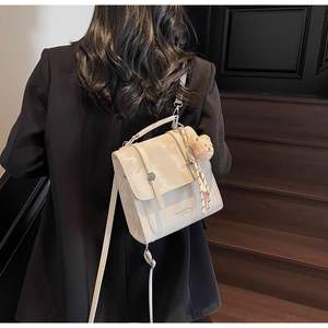 Model wearing a beige PU leather backpack with silk scarf and teddy bear charm on wood stairs