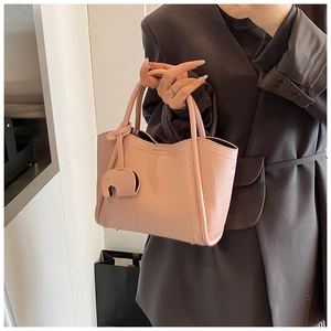 Pink lychee texture leather tote bag detail with elephant charm and brand logo