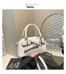 Close-up of white minimalist shell bag with metal buckle and adjustable strap