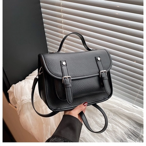 Detail view of black lychee texture leather satchel with silver buckles and top handle