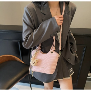 Close-up of pink bucket bag with wave texture, logo detail and cute bear charm pendant