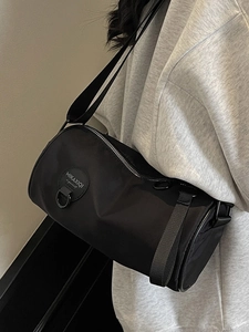 Minimalist black nylon cylinder crossbody bag with adjustable strap and round logo