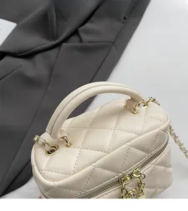 Détail du sac boîte matelassé beige avec chaîne en métal doré et double fermeture éclair