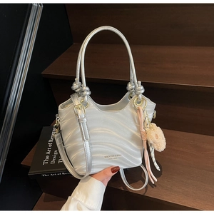 Detailed view of silver metallic bucket bag with wave patterns and plush heart charm