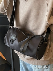 Minimalist black cylinder nylon crossbody bag with adjustable wide strap and round logo