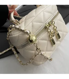 Gros plan détaillé sur la texture en cuir beige matelassé et chaîne dorée du sac de luxe