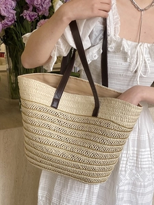 Large beige woven straw tote bag with brown leather straps for summer beach vacation