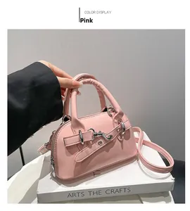Detailed close-up of a pink shell-shaped crossbody bag with metallic buckle and leather handle