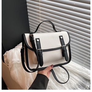 Detail of white lychee pattern leather satchel with black straps and silver hardware