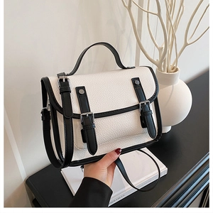 Close-up of vintage messenger bag with white lychee grain leather and black buckle straps
