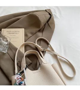 Detail of adjustable litchi texture shoulder strap on a beige crossbody bucket bag