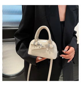 Detail of creamy beige mini shell bag with silver hardware on a black suit model
