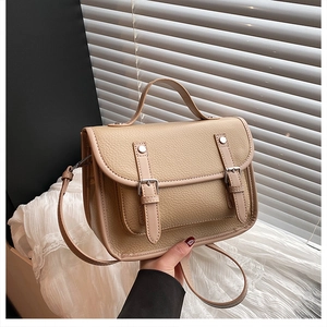 Close-up of beige lychee grain leather crossbody bag with silver buckles and handle
