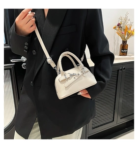 Detail of cream white mini shell bag with silver buckle worn with a black blazer