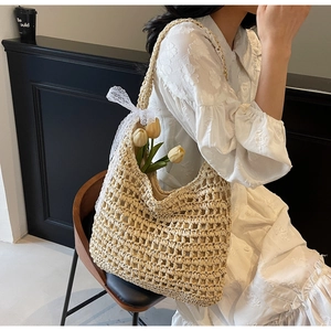 Close-up of hollow straw woven tote bag with white lace bow and delicate floral detail