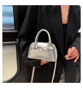 Detail of metallic silver shell bag with leather strap buckle and silver hardware