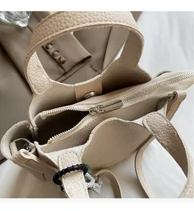 Detail view of beige lychee leather bag featuring a smooth silver metal zipper closure