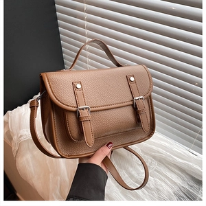 Detail showing high-quality lychee pattern leather and dual buckle design of the messenger bag