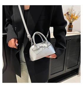 Detail of a metallic silver shell bag with adjustable strap on a dark blazer