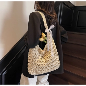 Detail of hollow woven tote bag featuring a white lace bow and elegant floral decoration