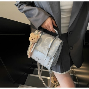 Detail of silver backpack with marble pattern flap, metal handle and cute bear charm