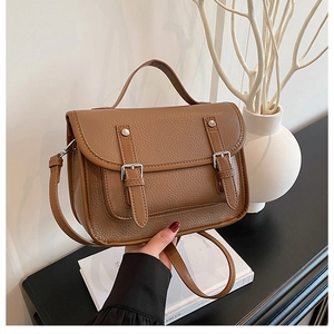Close-up of brown litchi pattern leather satchel showing vintage buckle details