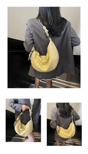 Detail of light yellow pebble leather hobo bag with knotted strap and teddy bear charm